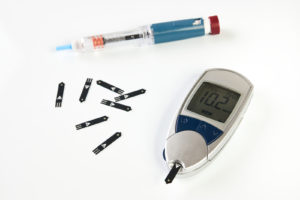 Diabetes patient using a glucometer for blood sugar testing with test strips and lancets.