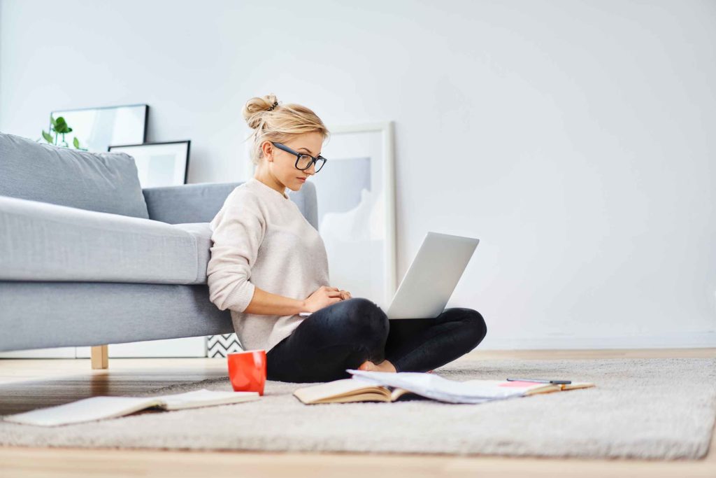 Young woman sitting on floor, doing work