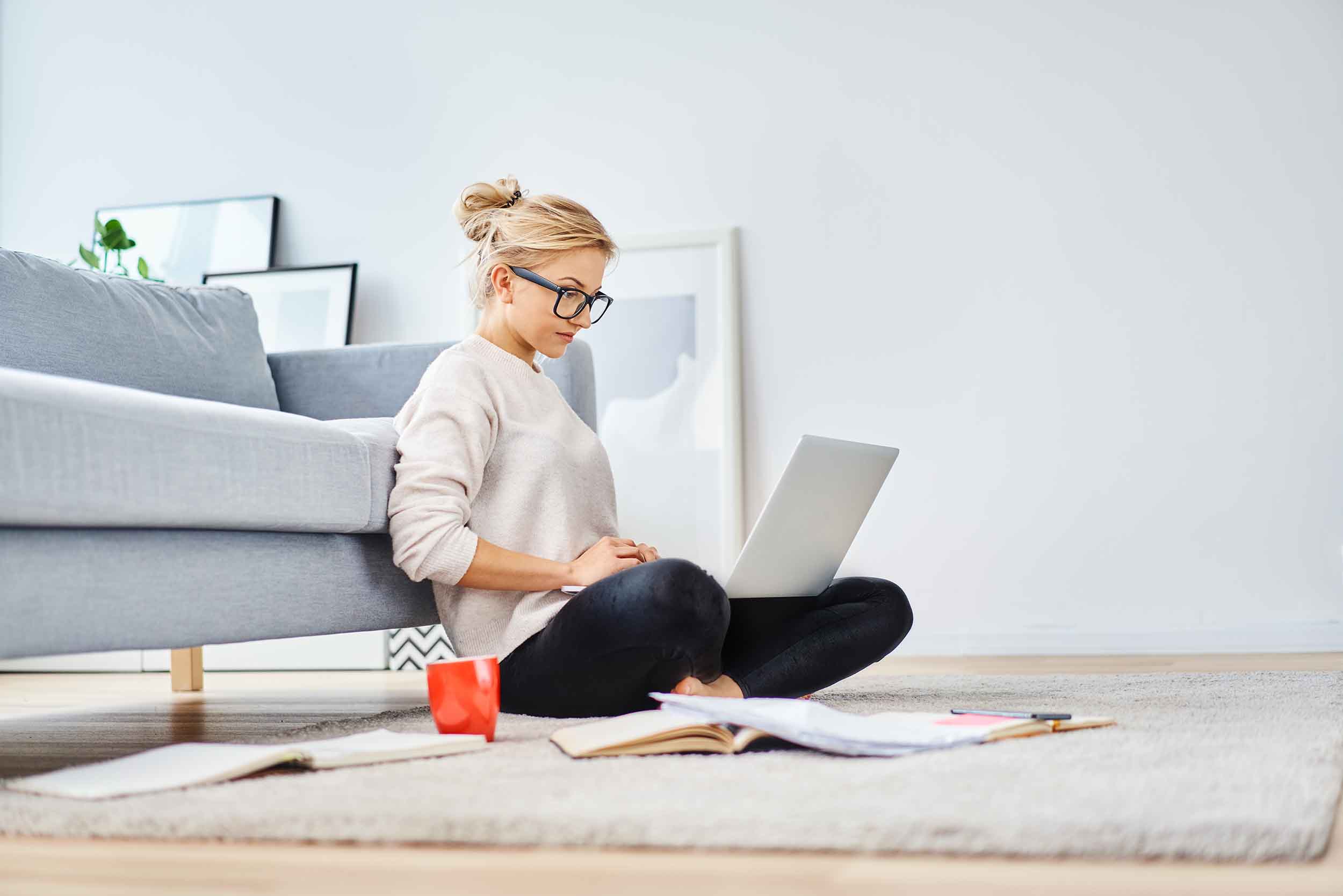 Young woman sitting on floor, doing work