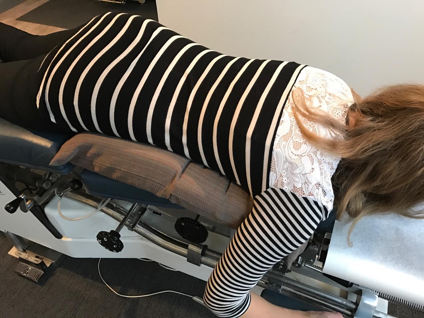 Prenatal chiropractor providing gentle spinal adjustment to a pregnant patient.